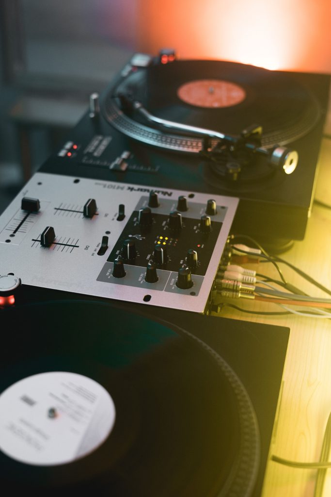 pexels photo 5118431 5118431 Close-up of a DJ setup with turntables and a mixer in a vibrant indoor setting.